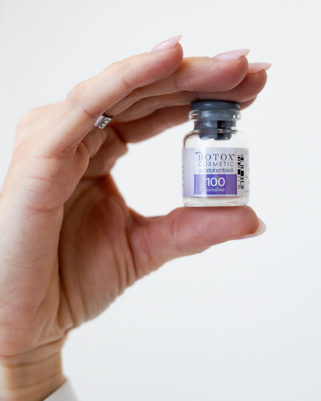 A woman's hand holding vile of Botox.